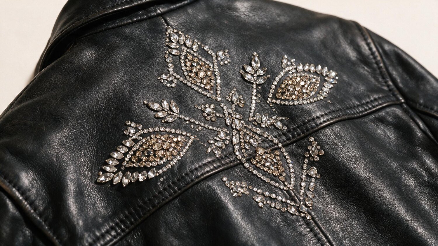 An original botanical motif built from densely set crystals on a black leather panel